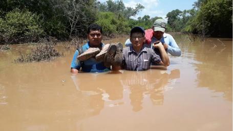 三个人走过洪水泛滥的河流。