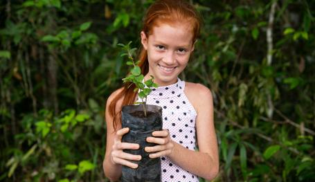 9岁的Marlice Soares抱着一棵当地的树苗，这种树苗是她在巴西亚马逊的农用林业系统中种植的