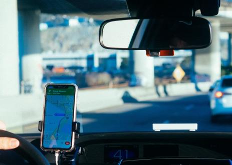 一名司机在汽车后座拍摄，通过安装的智能手机跟踪GPS导航。
