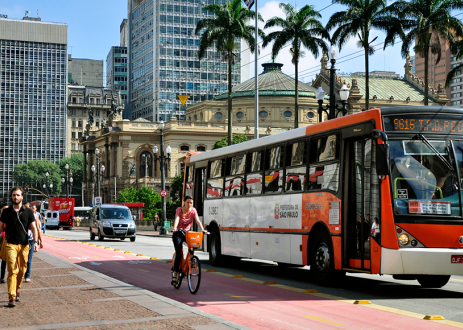 公共汽车在自行车道旁边，行人在人行道上行走。