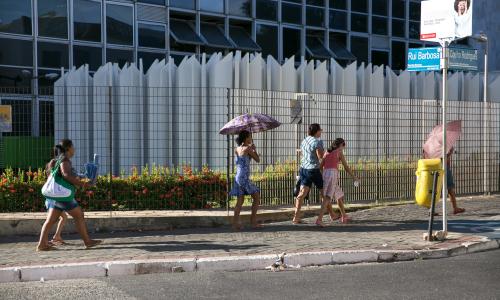人拿着伞走在人行道上在一个阳光明媚的一天。